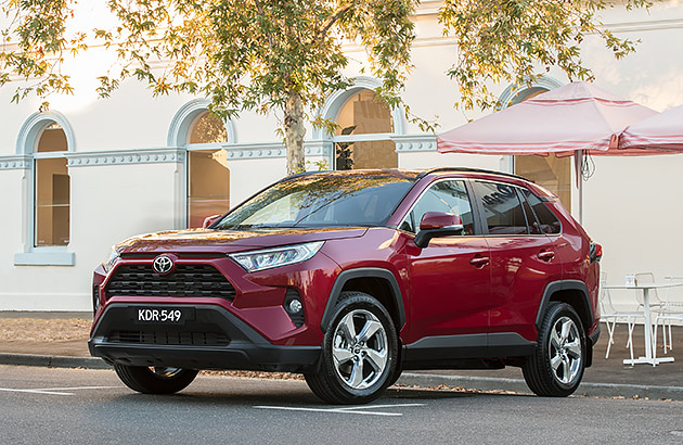 A red Toyota RAV4 GXL in front of a restored old building