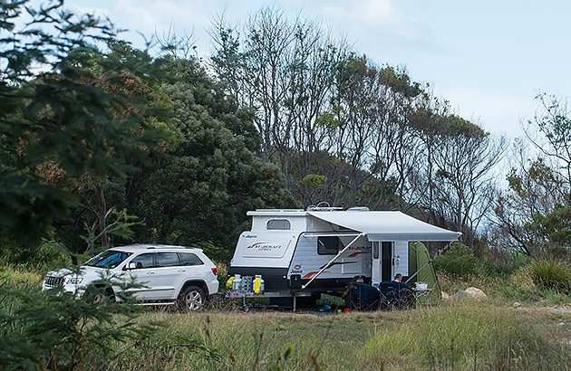 A caravan parked in bushland with an awning extended