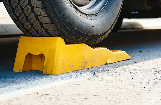 A caravan wheel raised on a yellow wheel chock