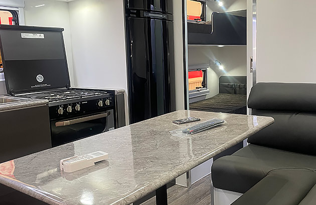 Interior of a new caravan showing a kitchen table and bunk beds in the background