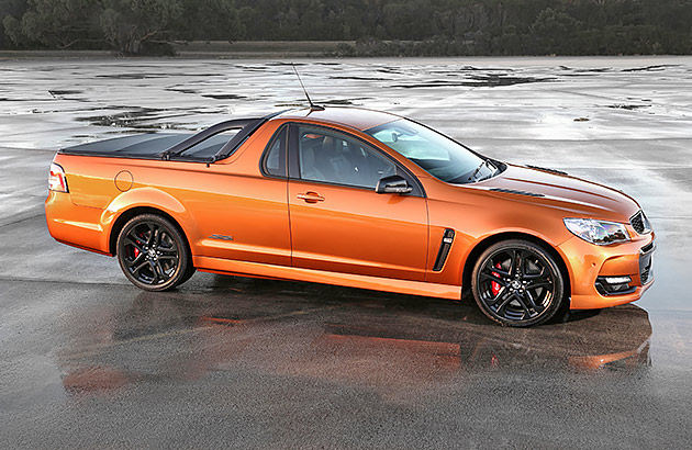 A metallic orange Holden Commodore ute on a wet tarmac