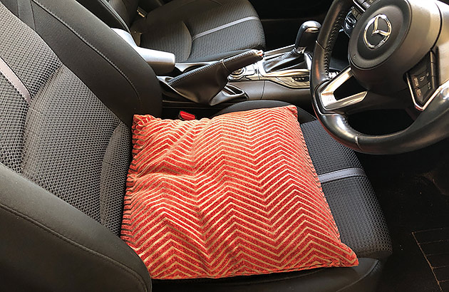 A red cushion on a driver's car seat
