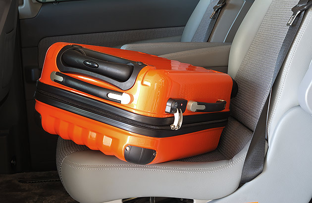 An orange-coloured hard suitcase on a car seat