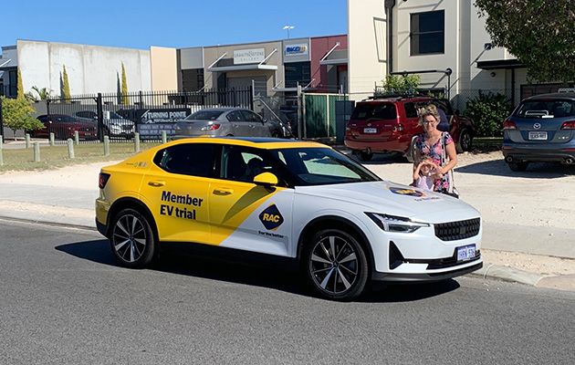 Polestar 2 electric vehicle parked on side of the road with a woman standing beside it