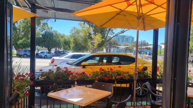 View from inside cafe looking out onto street with yellow Polestar 2 electric car in background
