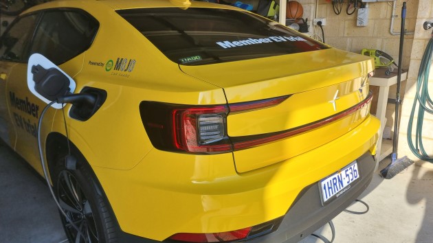 Yellow Polestar 2 electric car charging using domestic port in home garage