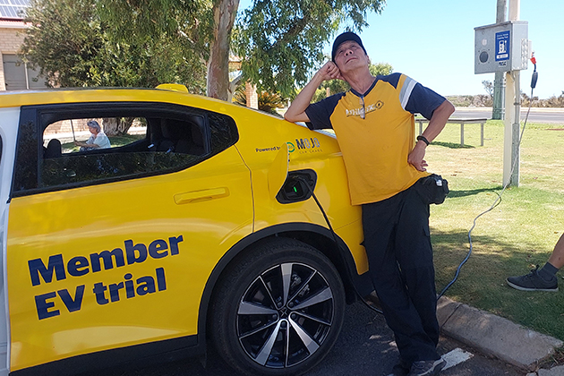 A man posing beside an electric vehicle