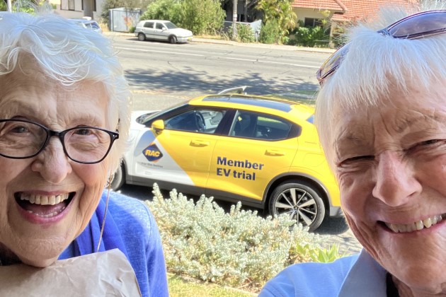 Close up of two older women smiling with yellow Polestar 2 electric car in background