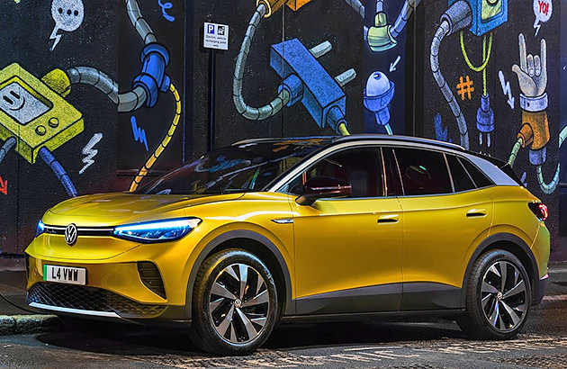 A gold Volkswagen ID.4 in front of a wall covered in street art