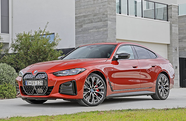 A red BMW i4 parked in a driveway