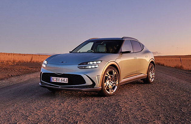 A grey Genesis GV60 parked on a gravel road in the country