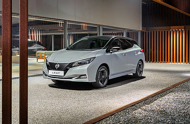 A white Nissan Leaf in the driveway of a modern home