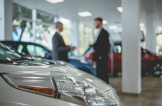 Two men talking in a car showroom