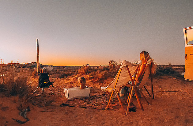  A woman sitting on a camp chair watching a sunset