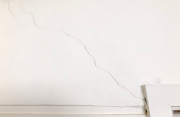 A diagonal crack in a wall over a door frame