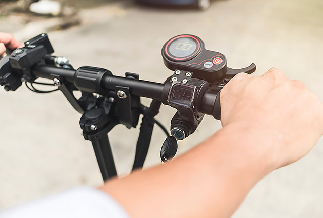 A person's hands on the handlebars of an e-scooter