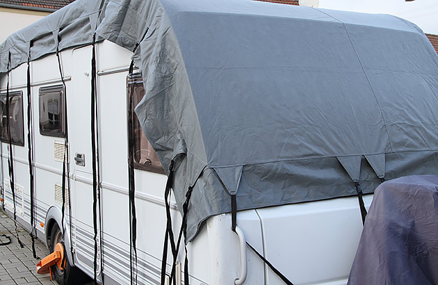 A caravan with a grey cover over the roof