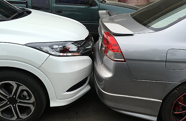 Two cars collide bumper-to-bumper on a road