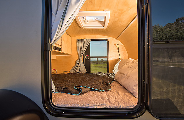 The interior of a teardrop camper showing the bedding