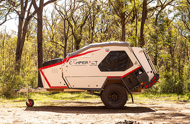 A pod style camper near tall trees