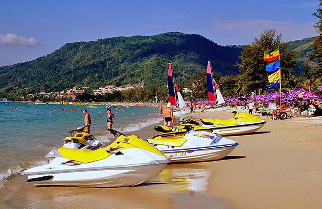 A row of yellow and white jet skis on a beach