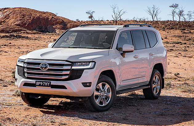 A white Toyota Landcruiser parked in a scrubland area