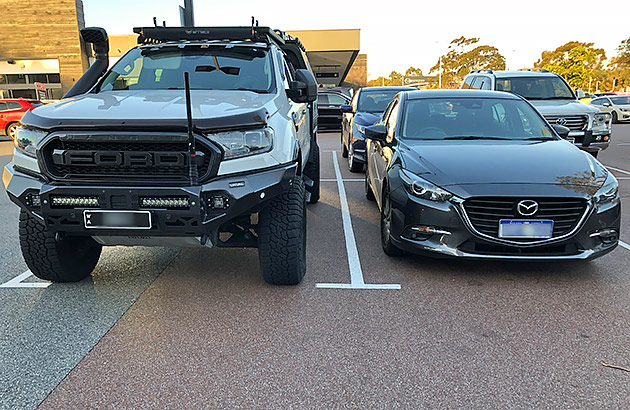 A Ford Range parked next to a smaller Mazda 3