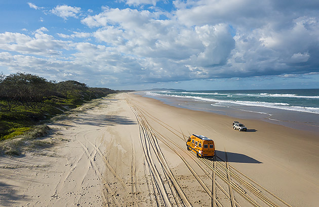 A yellow van driving on a beach