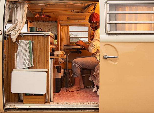 Someone cooking in the doorway of a VW Kombi van