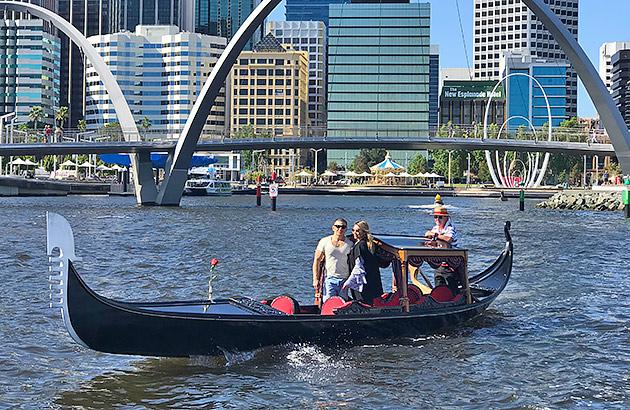 A couple ride in the gondola with Elizabeth Quay in the background