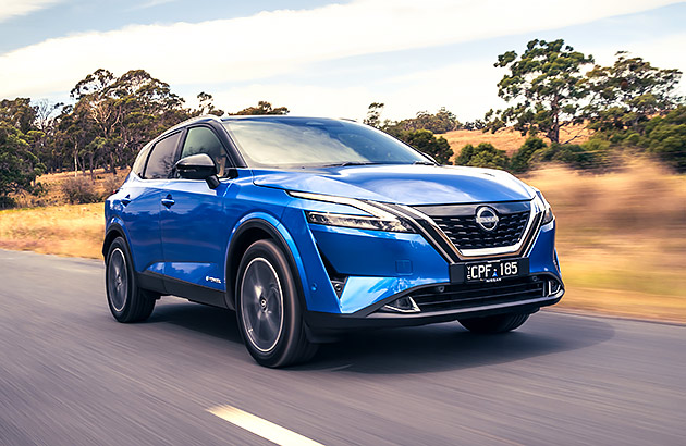 A blue Nissan Qashqai driving on a country road