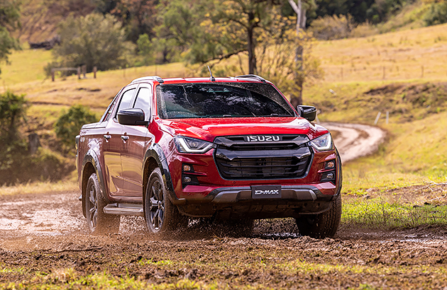 A red Isuzu D-Max driving on a muddy track