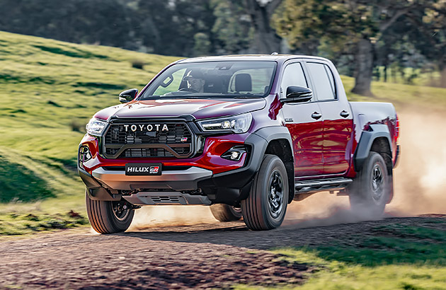 A red Toyota Hilux on a gravel country road