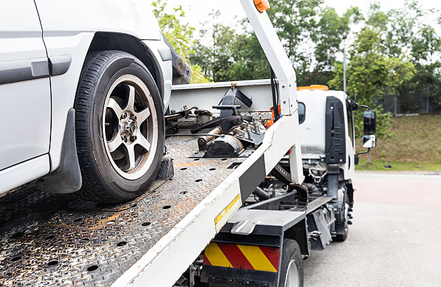 A white car loaded on to the back of a flatbed tow truck