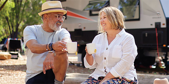 A couple sitting on a log in front of a caravan