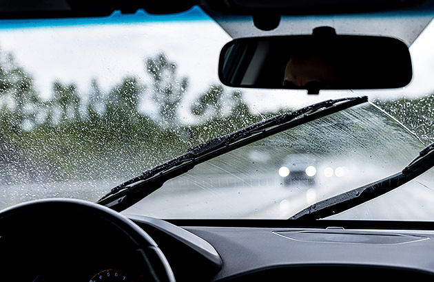 A car driving in rain approaching another car with its headlights on