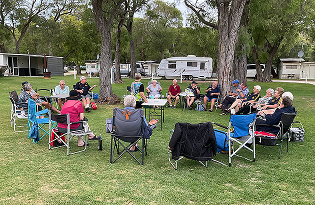 A group of caravanners sitting in a circle socialising in a caravan park