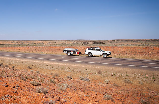 A car towing a small trailer on an outback road