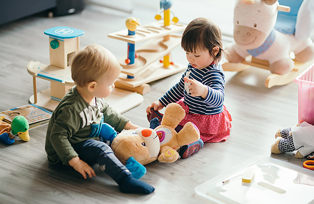 Two young children playing with toys in a lounge room