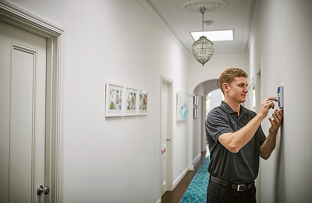 A security installer fixing a home security panel to a wall