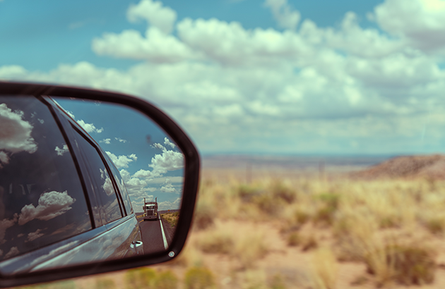 A car's rear view mirror showing a truck