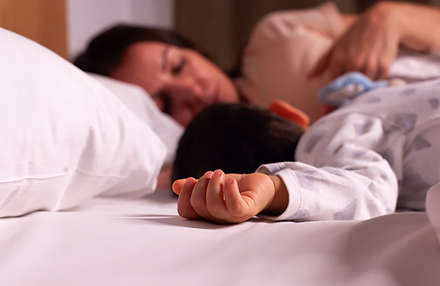 A young mother asleep with her baby next to her