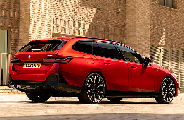 A red BMW i5 parked in front of a brick wall