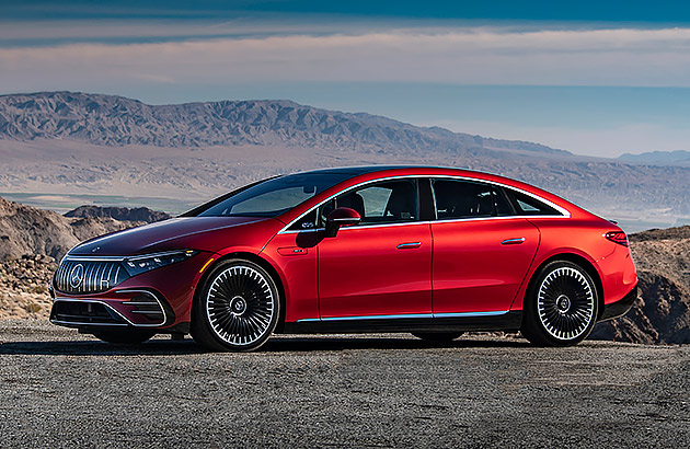 A red Mercedes Benz EQS parked in a barren landscape