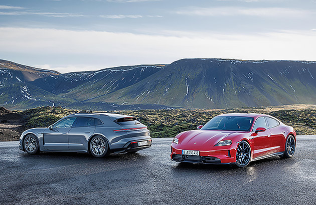 A grey and red Porsche Taycan parked on a road in front of a mountainous landscape