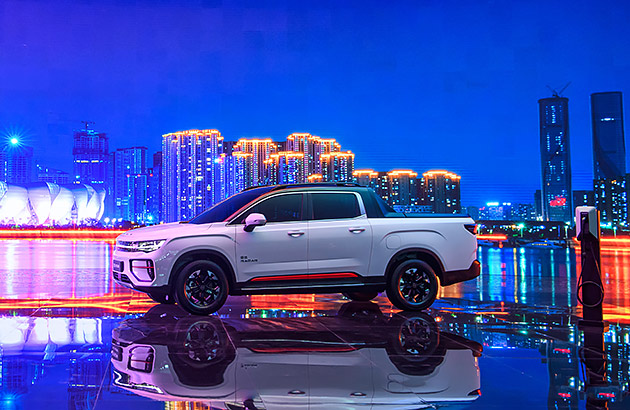 A white Geely Radar parked in front of a cityscape at night