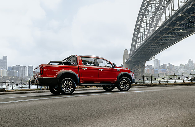 A red JAC T9 parked on a road under a bridge