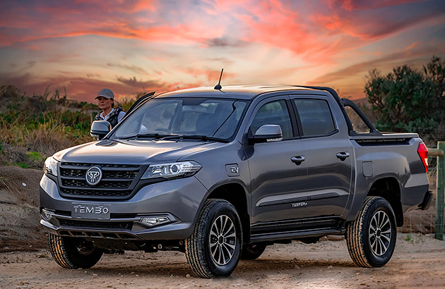 A dark grey Tembo Tusker parked in a rural setting at sunset