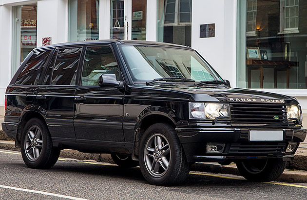 A black 1990s Range Rover on a city street