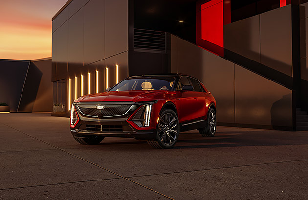 A red Cadillac Lyric in front of a modern building